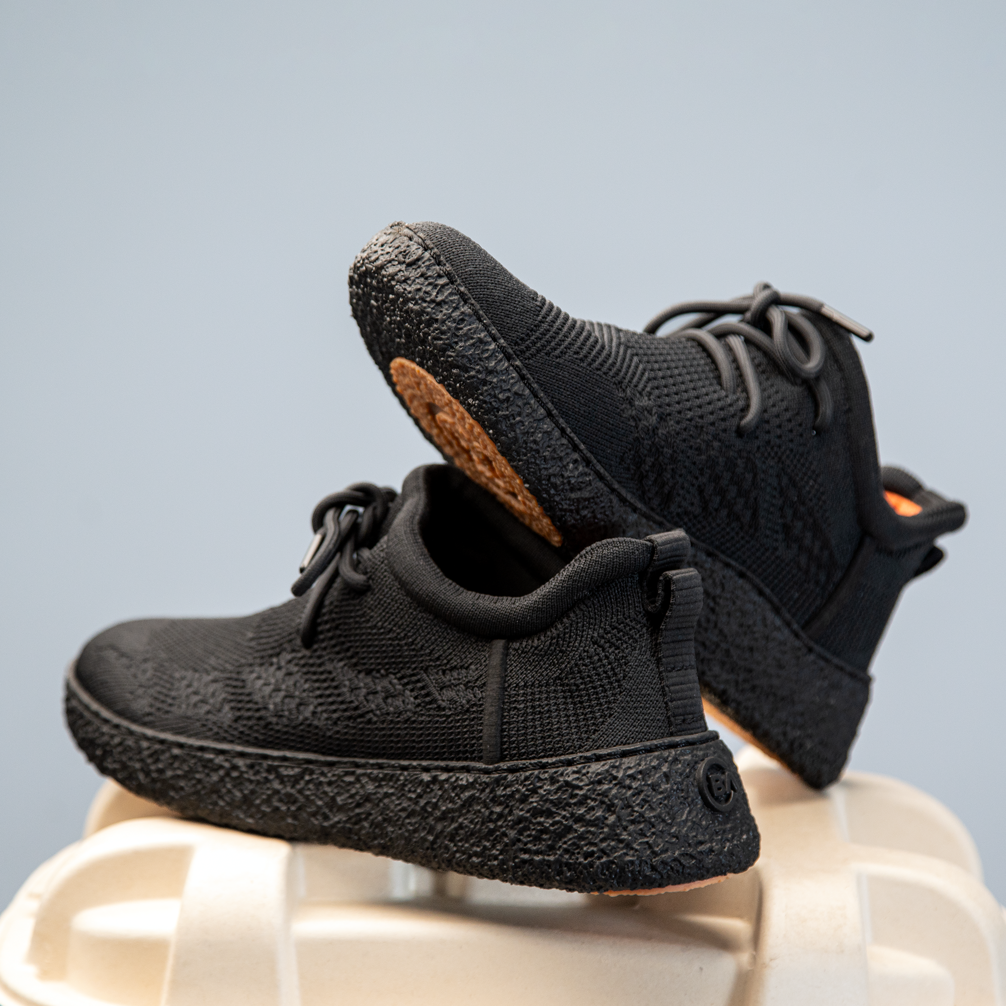 Full black Baliston Smart Shoes on top of recycled packaging