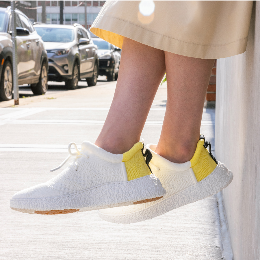 White/yellow Baliston Smart Shoe on woman with legs crossed